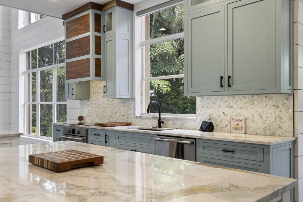 A kitchen with marble counter tops and blue cabinets.
