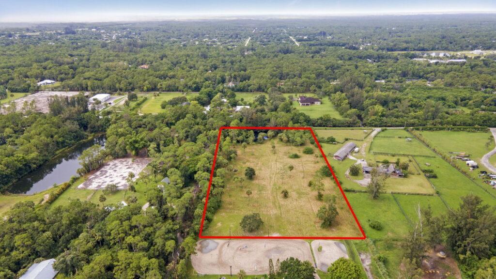 A large field with trees and a red line in the middle.