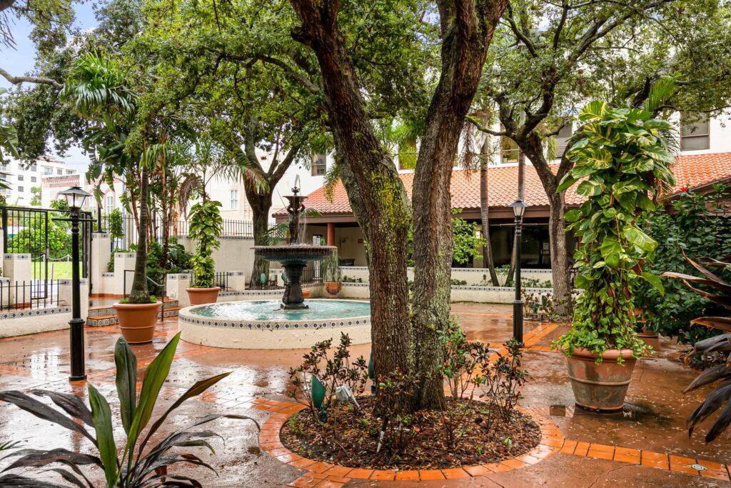 A tree in the middle of a courtyard with water fountains.