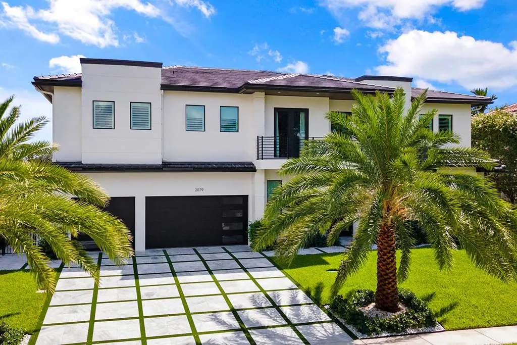 A large white house with palm trees in the yard.