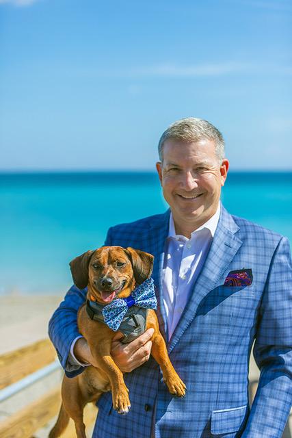 A man holding his dog on the beach